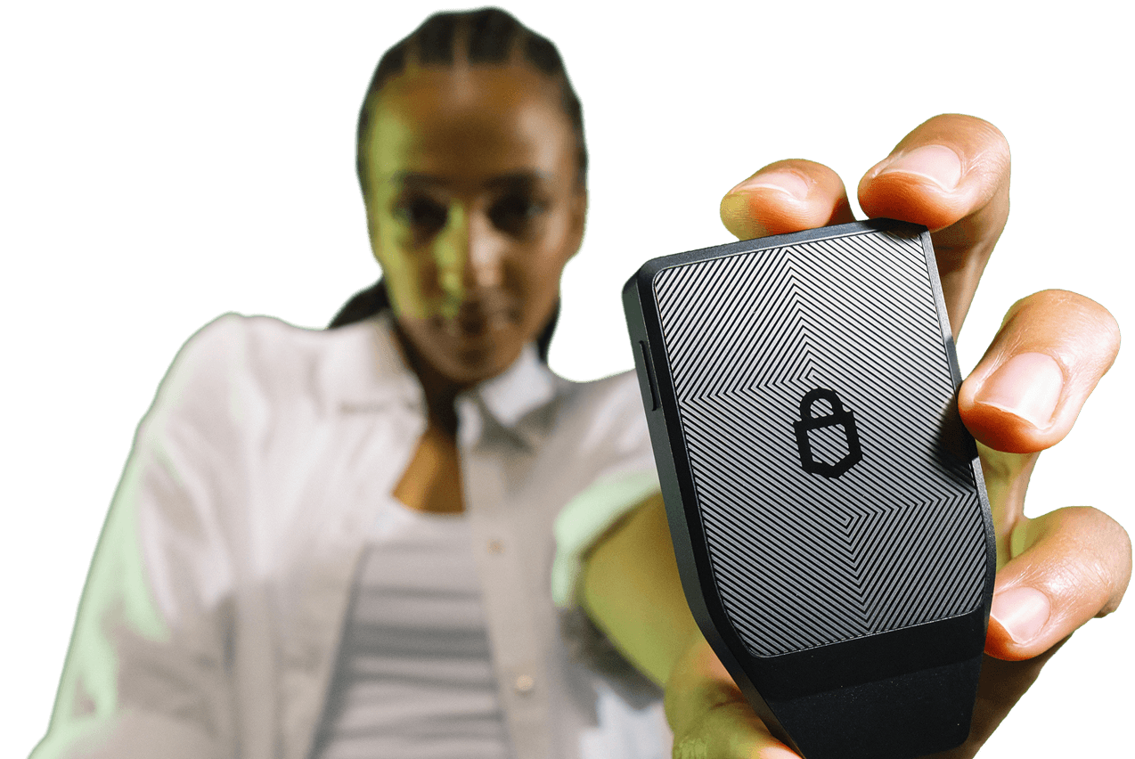 Blurred man holds a black patterned electronic device close to the camera.